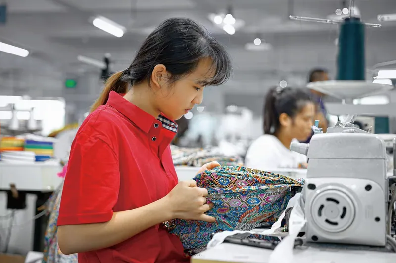 A sewing operator handling patterned fabric at 颖尔服饰