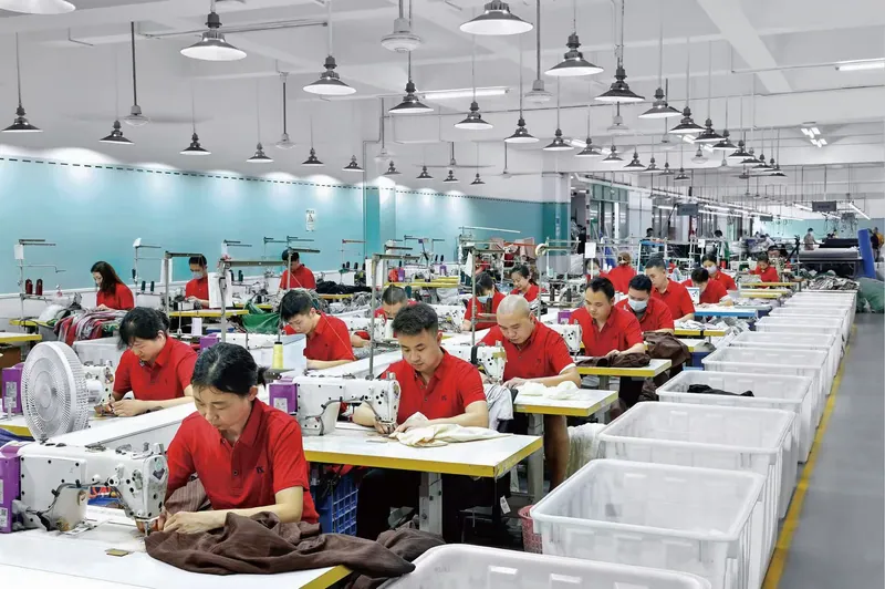 Garment sewing workstations and staff in the 颖尔服饰 workshop